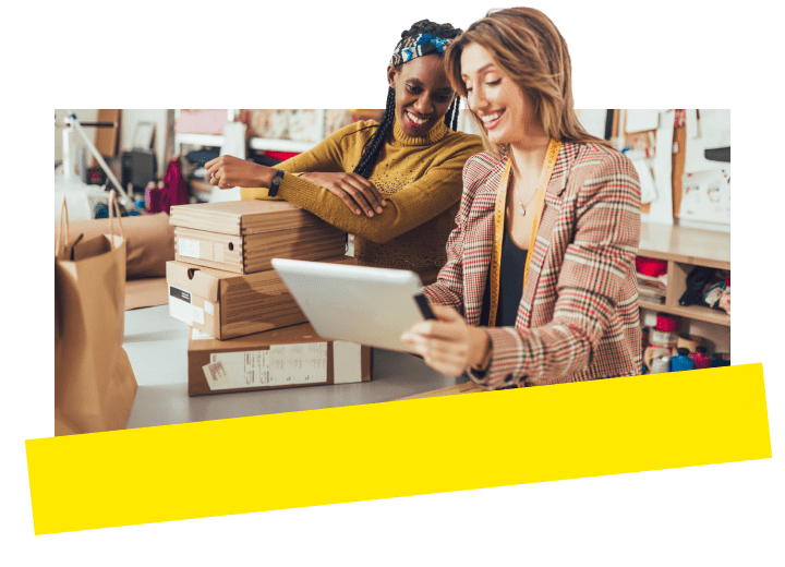 Eine Unternehmerin sieht sich Kundendetails auf einem Tablet an, während eine Kollegin GoTo Connect Customer Engagement nutzt.