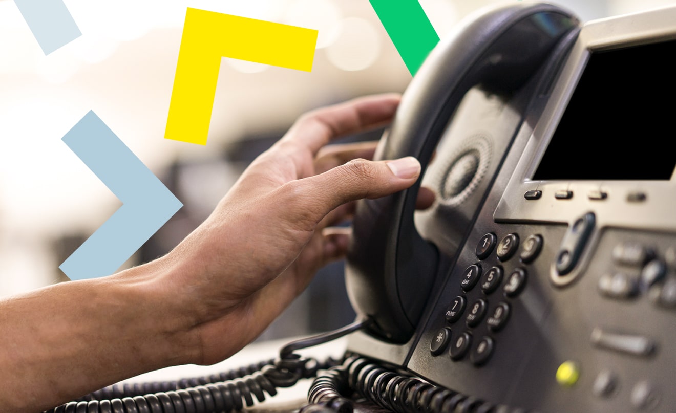 Hand picking up desk phone to answer a call.