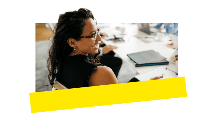 Eine Mitarbeiterin nimmt lächelnd an einem Anruf in einem Konferenzraum teil.