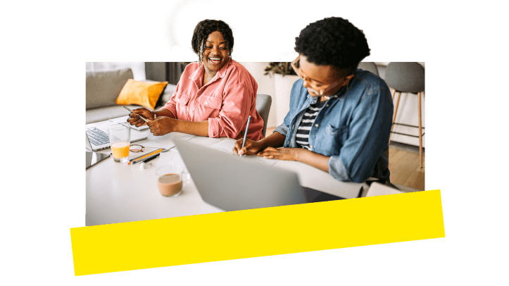 Zwei Kollegen arbeiten lachend per Fernzugriff zusammen.